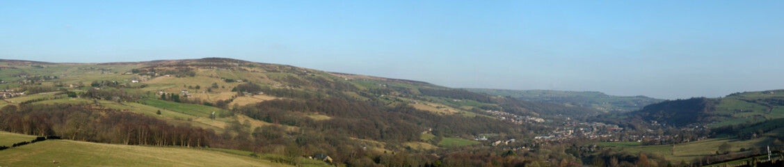 Fototapeta na wymiar panoramic view of the calder valley in west yorkshire with the town of mytholmroyd surrounded by fields, woods and moorland