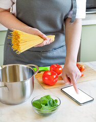 female hands preparing ingredients for pasta on a wooden board. cooking spaghetti with tomatoes and spinach