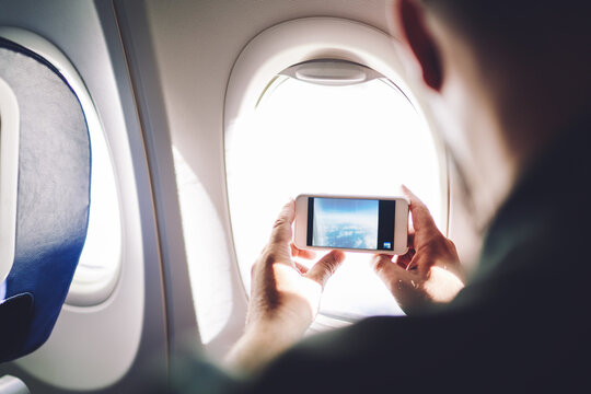 Man taking picture through airplane window of scene outside