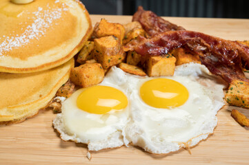 Diner style slam breakfast.  Two eggs sunny side up, bacon, hash browns, and two pancakes.