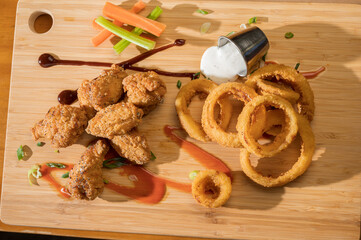 Chicken wings and onion rings with a pitcher of beer.