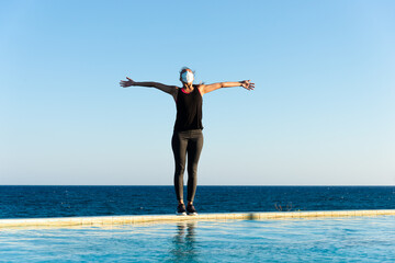 Young woman with protective surgical face mask performing yoga stretching exercises outdoor during covid-19 coronavirus pandemic