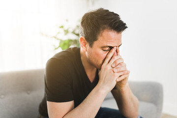 Depressed man thinking at home on couch