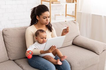 Frustrated African Mom With Sick Baby Using Tablet At Home
