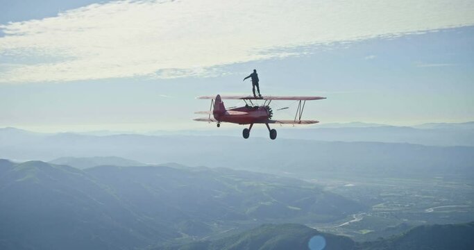 Vintage plane does flips with stuntman riding on top, aerial