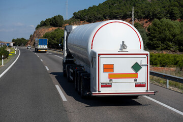 Camión cisterna de mercancías peligrosas que transporta gas licuado circulando por la carretera...
