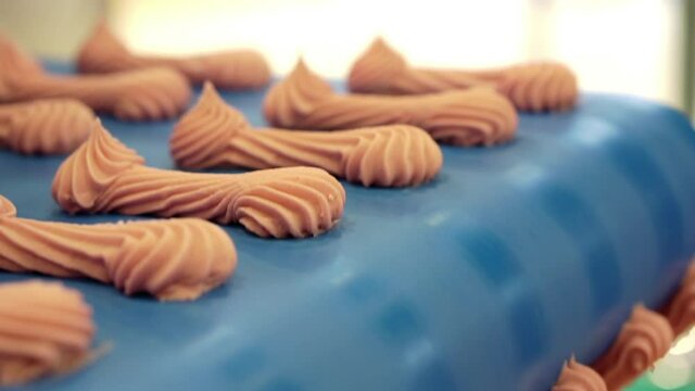 Moving conveyor belt with pink meringues. Marshmallow production line. Shallow depth of field.