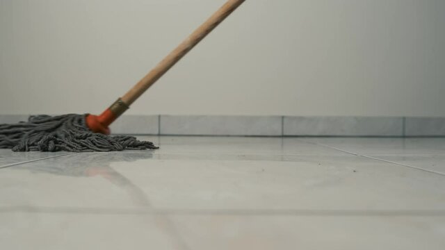 Close-up frame of a mop moving on the floor on a tile. Cleaning and cleanliness