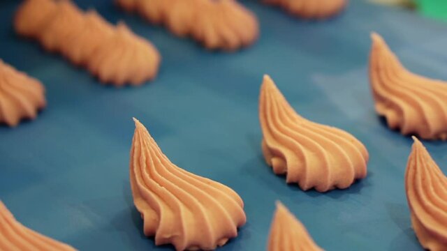 Moving conveyor belt with pink meringues. Marshmallow production line. Shallow depth of field.