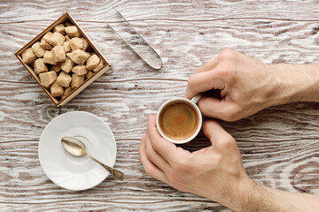 Man's hands holding cup of coffee on the wooden table