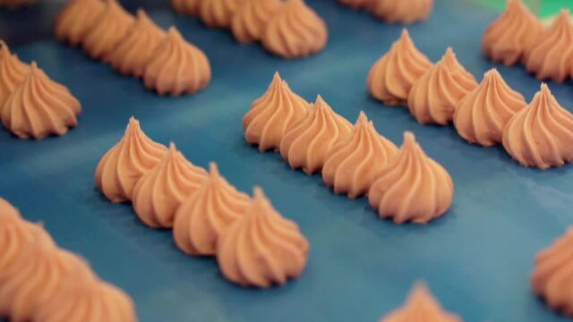 Moving conveyor belt with pink meringues. Marshmallow production line. Shallow depth of field.