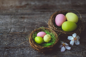 Easter quail painted eggs  in a nest and spring flowers on a  wooden background.   An Easter card with a copy of the place for the text.Top view.