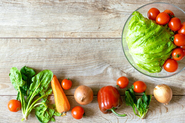 Bowl of organic and bio fresh vegetables tomato, peppers, carrots lies in row on rustic wooden background table with copy space. Healthy natural ripe vegetarian vegetables concept. Salad ingredients