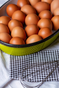 Iron basket for field eggs on the table with a metal whisk.