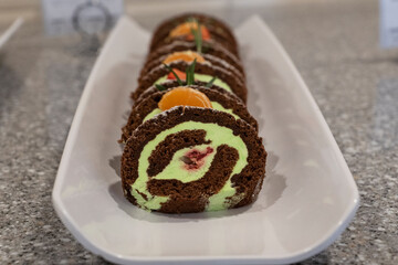 Pieces of round cakes with tangerines lie on white plate.. Desserts for celebration holidays, buffet and catering. Sweat unhealthy food.