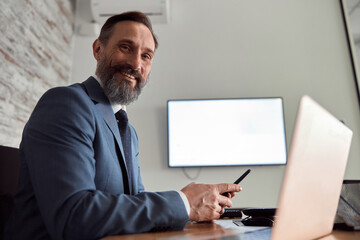 Happy adult caucasian man is working in a modern office