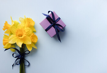Bouquet of narcissus with gifts on blue background top view flat lay. International Women's Day,