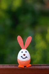 Easter egg with bunny ears. Easter decoration in a garden. Selective focus.