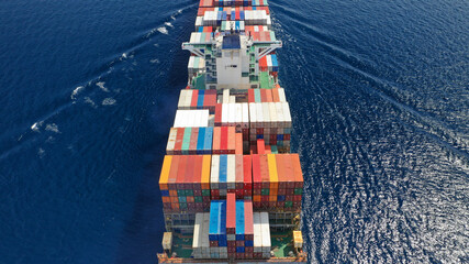 Fototapeta premium Aerial drone top view of fully loaded container ship cruising open ocean sea for logistics import export, shipping or transportation