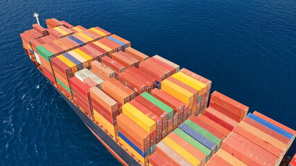 Aerial drone top view of fully loaded container ship cruising open ocean sea for logistics import...