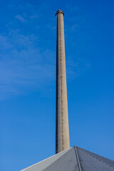 Huge chimney of an old disused and abandoned cement factory, sunny day with a blue sky in South Limburg, the Netherlands