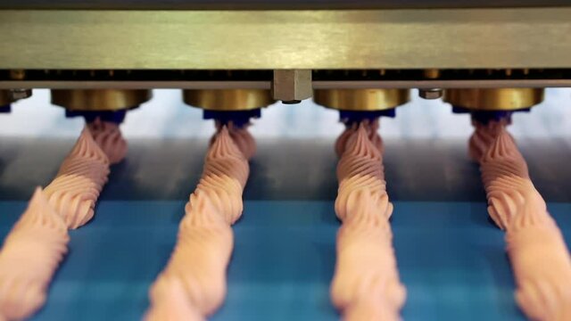 The molding machine squeezes the sweet cream onto the marshmallow conveyor line. Shallow depth of field.