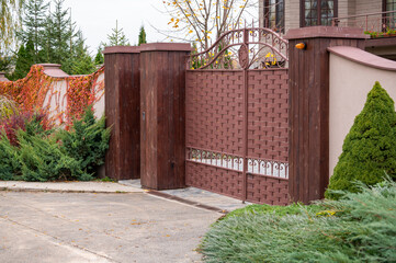 metal front gates with elements of forged parts with stone pillars, fencing of private territory