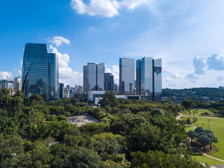Fototapeta premium Beautiful aerial view of modern architectural glass corporate buildings, trees of Parque do Povo park and São Paulo city skyline in sunny summer day. Concept of urban, cityscape, metropolis. Brazil.