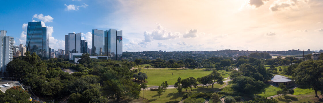 Beautiful aerial view of modern architectural glass corporate buildings, trees of Parque do Povo park and S&atilde;o Paulo city skyline in sunny summer day. Concept of urban, cityscape, metropolis. Brazil.