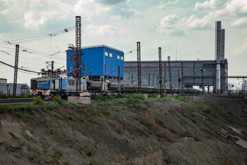 Obraz premium Rudny/Kazakhstan - May 14 2012: Open-pit mining iron ore. Railway train and diesel locomotive in quarry transporting ore to concentrating plant. industrial building on background.