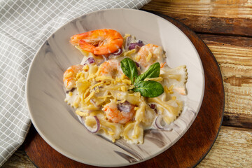 Pasta with shrimps in a creamy sauce on a plate with spinach on a table on a napkin