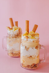 Delicate creamy banana dessert in a glass on a green background.