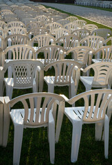 Rows of white chairs on a green meadow awaiting presses on a sunny day. conference