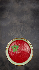 Top view of a bowl with beetroot cream soup / borscht with microgreen peas on a dark surface with copyspace