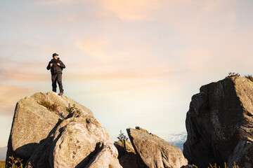 hiker man climbed on a rock in the mountain watching the sunset. mountain sports and activities. trekking. weekend getaway.