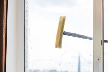 people, housework and housekeeping concept.cleaning window glass with sponge mop and foam.special brush, cleaning large open window .