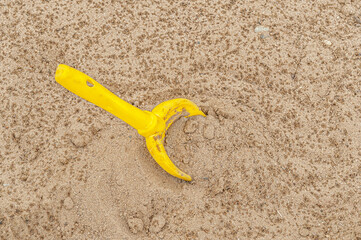 Fototapeta na wymiar child's yellow plastic shovel in the sand on the beach
