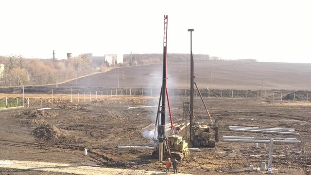 Excavation at a construction site, diesel pile driving machine with rumble and smoke drives piles deep into the ground to ensure the strength of the foundation of the future structure