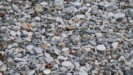 Sea coast view of rocks from above. Minimalistic background. Small sea pebbles. Texture is made of natural stones of different colors and sizes.