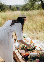 the woman takes food from the table. a girl in a white dress bent over for a snack. picnic in...