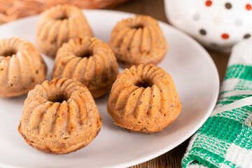 Close-up of lovely sweet cakes on white plate. White tea pot and rgeen cloth. Homemade baked sweets for snack or breakfast.