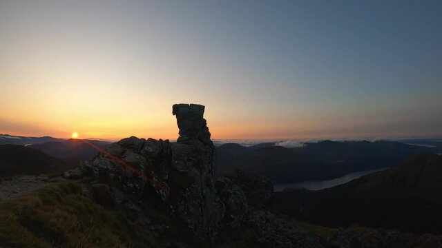 4k timelapse of sunrise at Cobbler mountain (Ben Arthur) in Arrochar Alps, Scottish Highlands. Clouds rolling over distant mountains, sun rising over horizon, Cobbler in foreground.