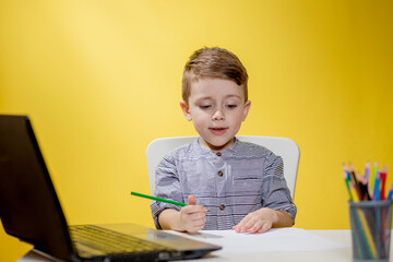Distance learning online education. A boy siting at home and does school homework, quarantine home distance learning.