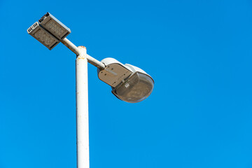 Street lamp on a lamppost against a blue sky, night lighting equipment for the city