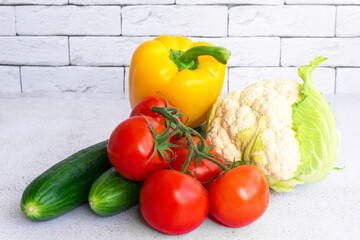 Assortment of healthy food, fresh green red yellow organic vegetables. cucumber, bell pepper, tomatoes, cauliflower on gray concrete background.