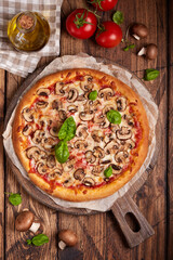 Pizza with mushrooms. American style homemade pizza with champignon mushrooms, mozzarella cheese and tomato sauce. Freshly baked and served with basil leafs. Vegetarian dish