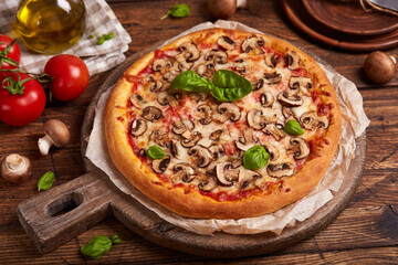 Pizza with mushrooms. American style homemade pizza with champignon mushrooms, mozzarella cheese and tomato sauce. Freshly baked and served with basil leafs. Vegetarian dish
