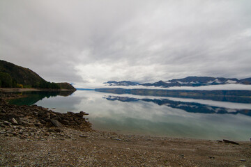 Lake Hawea, South Island of New Zealand. Pristine see- trough blue water reflecting the clouds and mountain mist