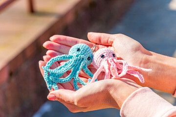 Knitted toy keychains, blue and pink knitted octopus keychains on a female hand close-up