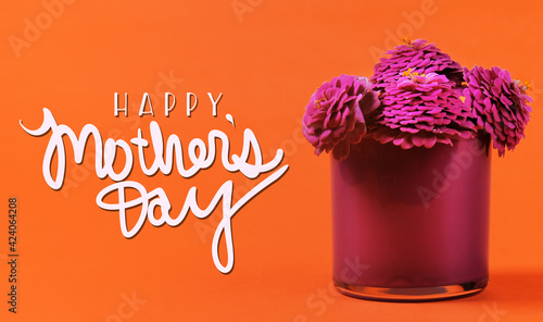 Happy Mother's Day bright orange background with pink zinnia flowers for holiday.
